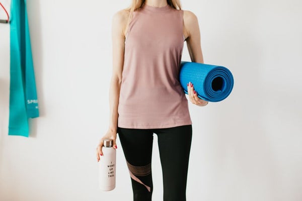 ボトルとヨガマットを持ったヨガウェアを着た女性