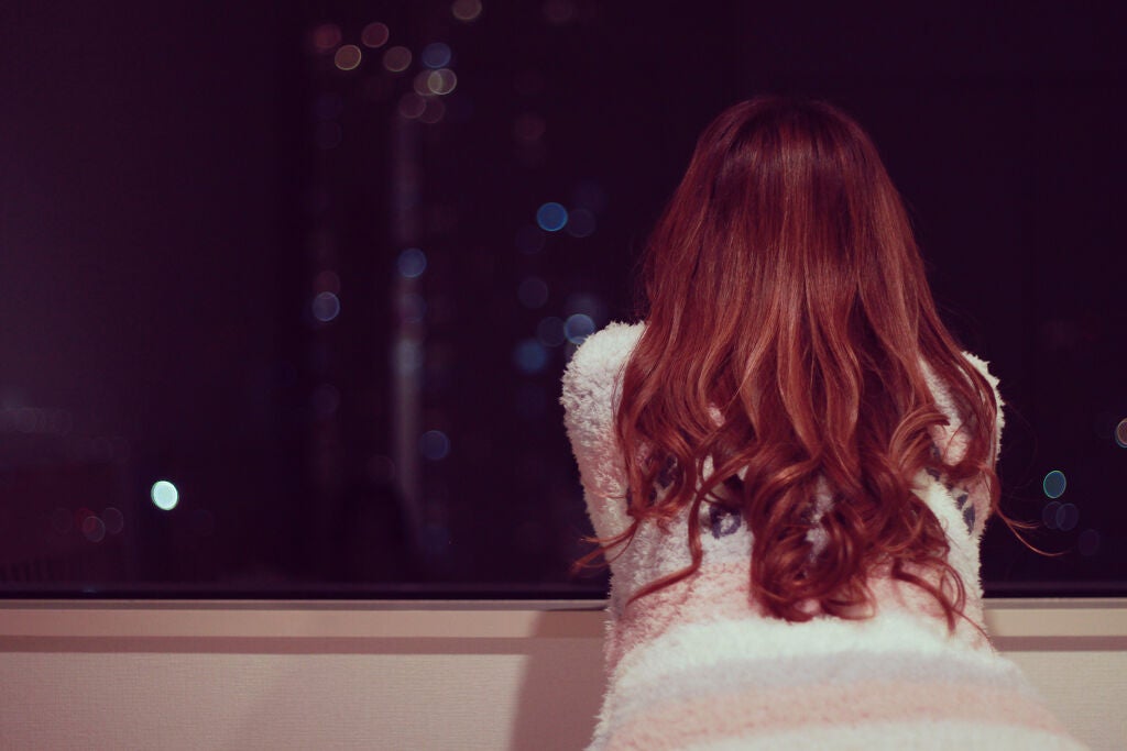 夜に窓の外を眺めている女性