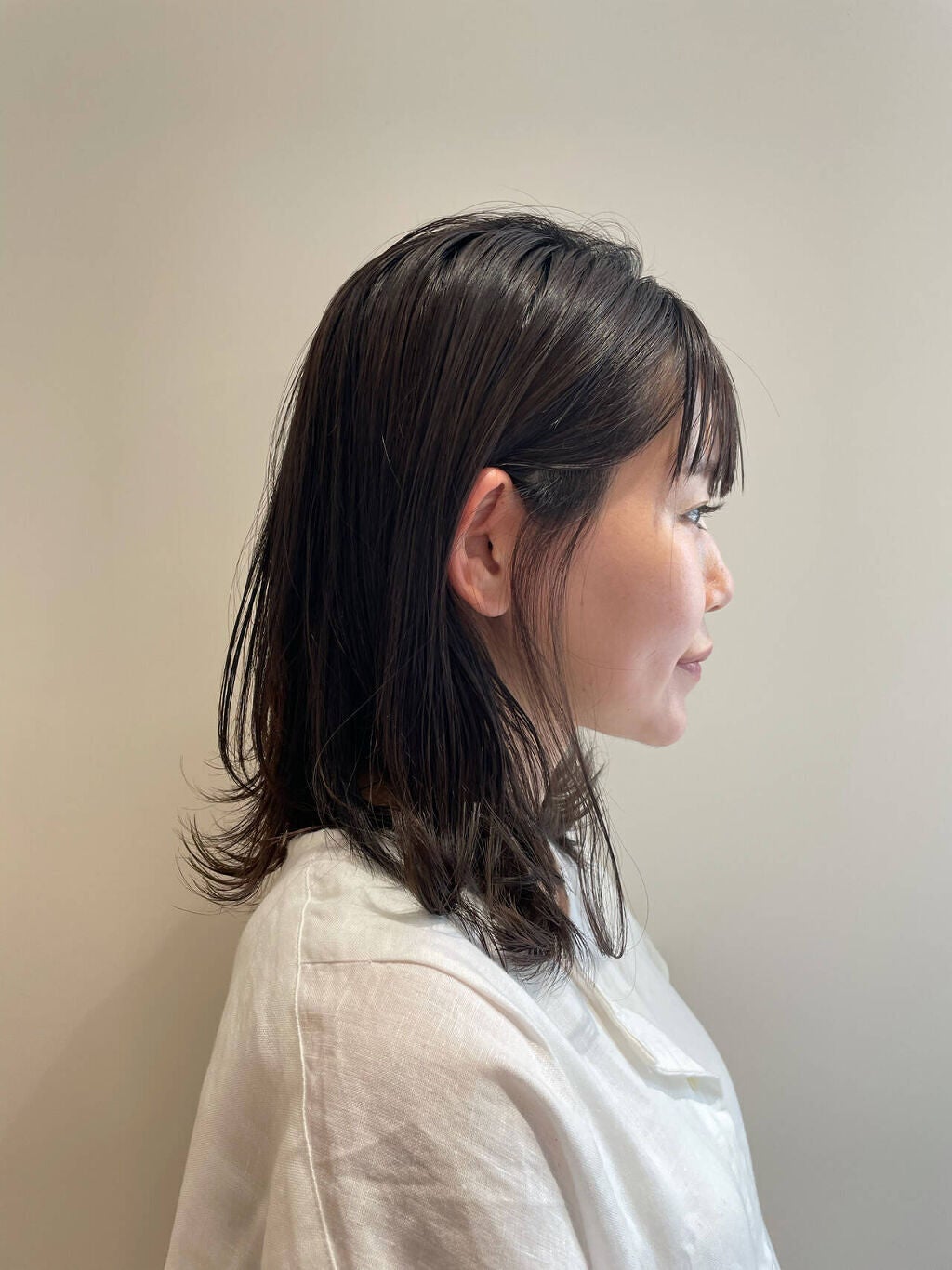 暗めアッシュグレーのミディアムヘアをした女性の横顔
