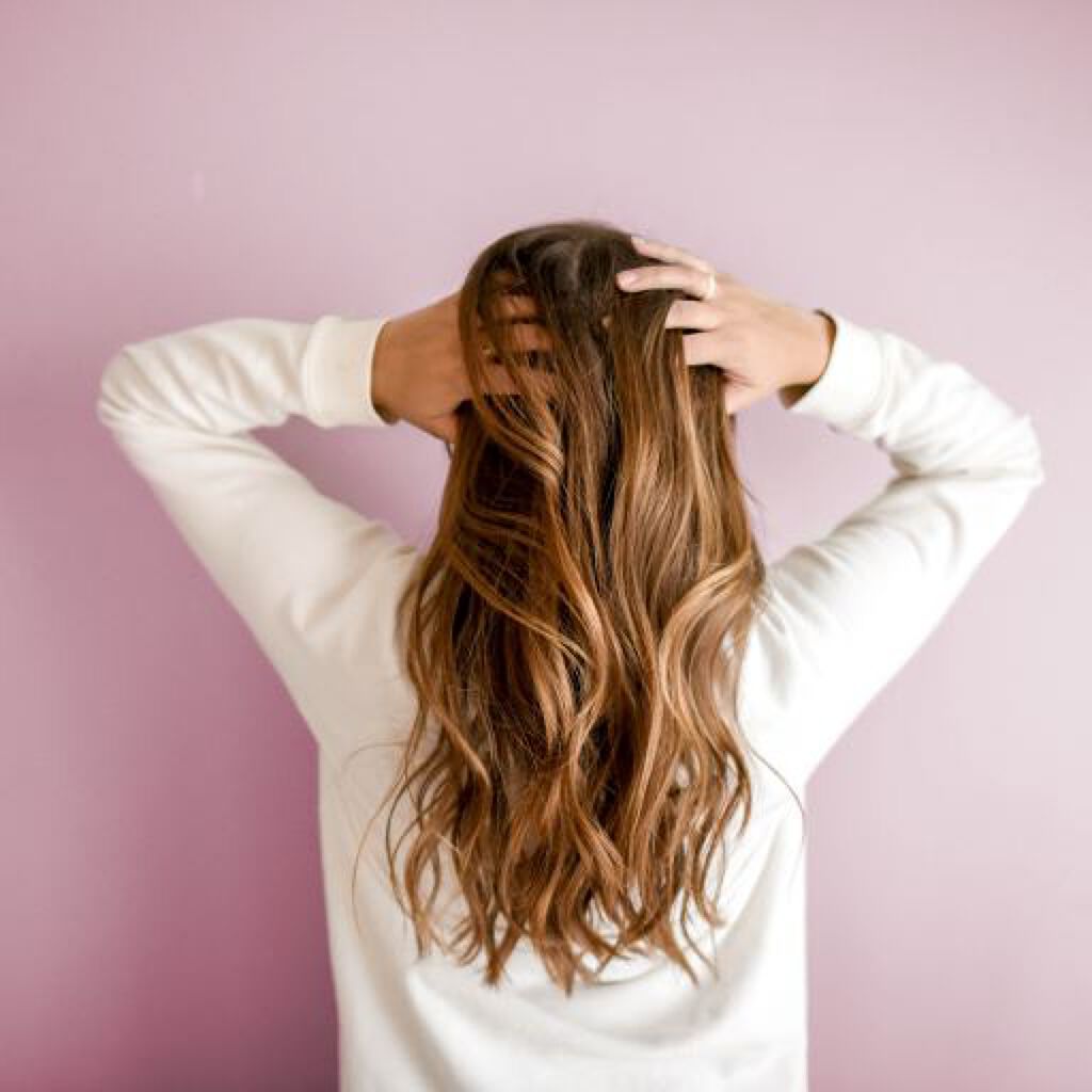 頭に手を当てる女性の後ろ姿