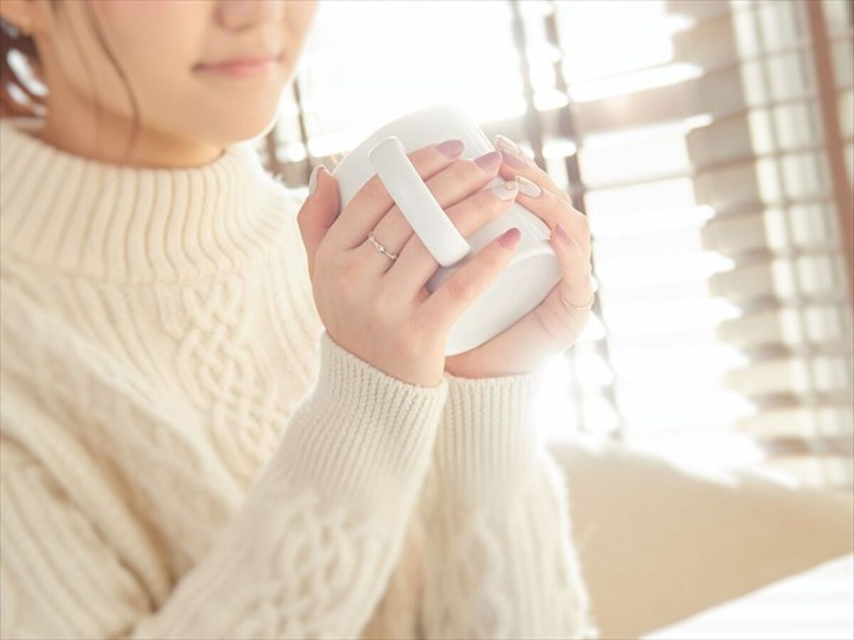 マグカップを両手で持つ女性