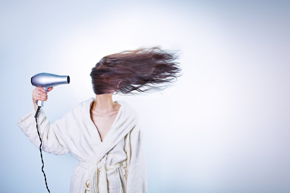 髪の毛をドライヤーで乾かしている女性