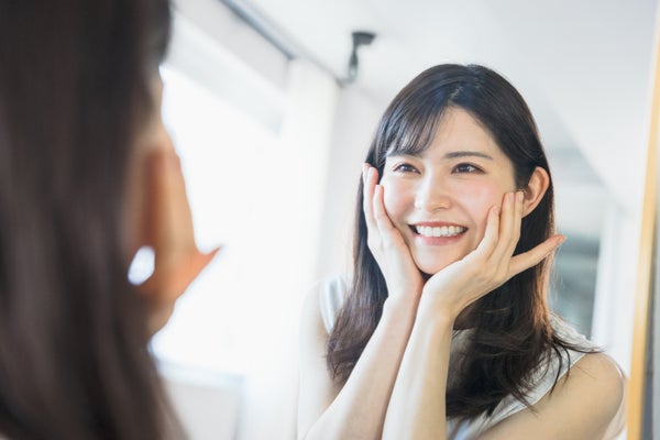 肌の調子が良くて嬉しくて頬に手をあてる女性