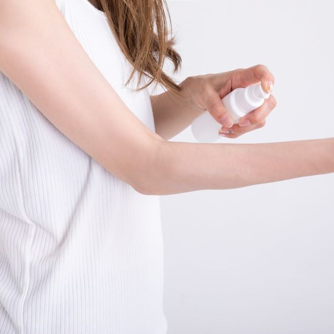 スプレーを腕に吹きかける女性