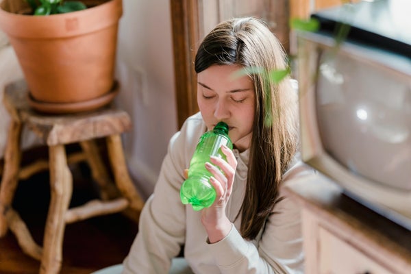 女性が緑色のペットボトルに入った飲み物を飲んでいる様子
