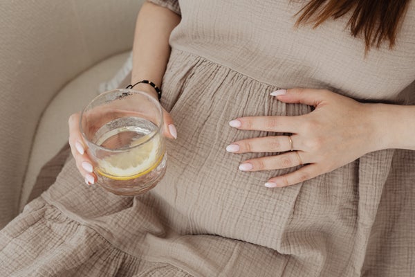 お腹を触りながらグラスを持つ女性