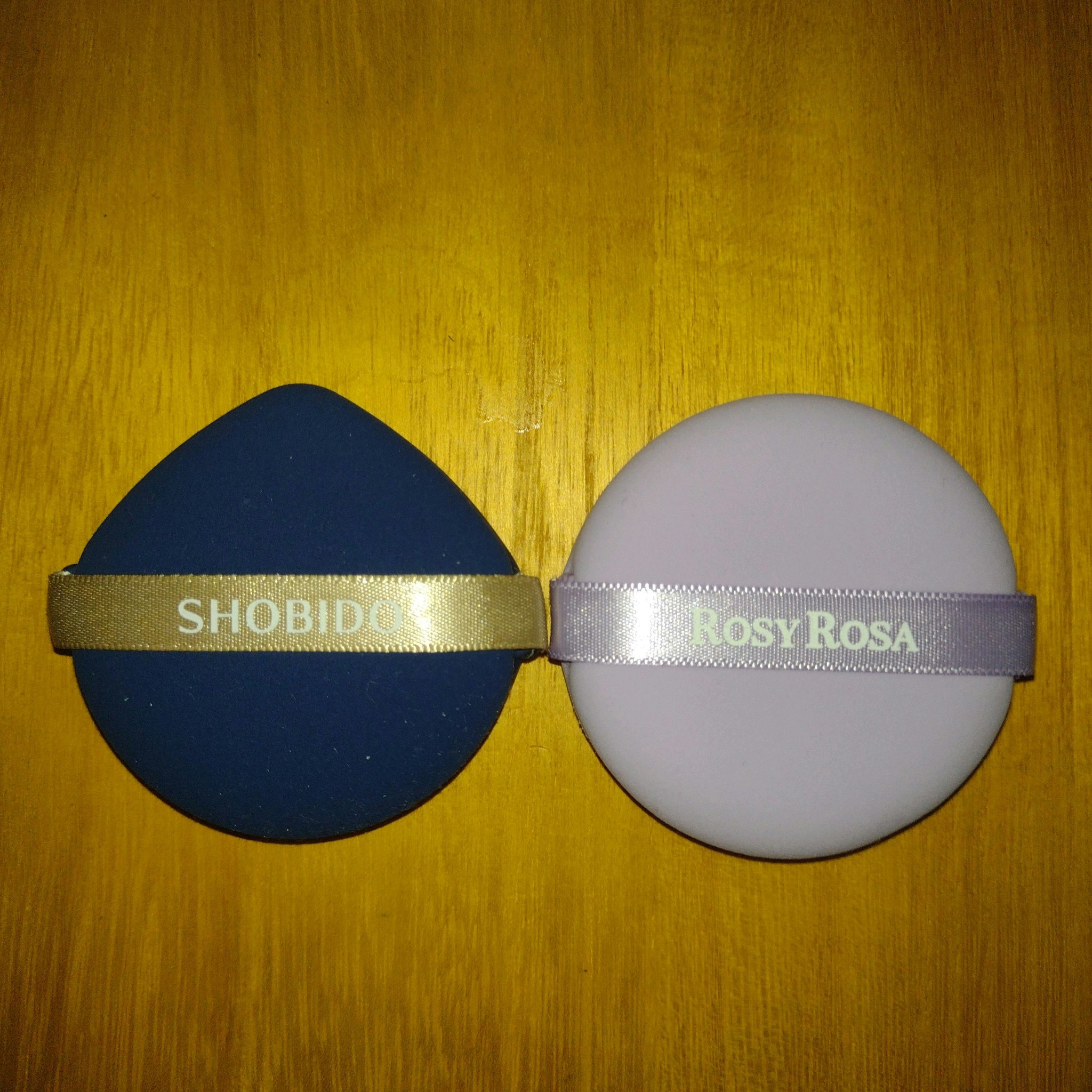 元々ロージーローザの全ファンデーション対応パフは愛用していて、今回パープルカラーが数量限定で出ていたので買ってみました。
薄いパープルで本当にかわいいです。

2つのパフの違いは
SHOBIDOは形がしずく型なので細かい所が塗りやすいです。