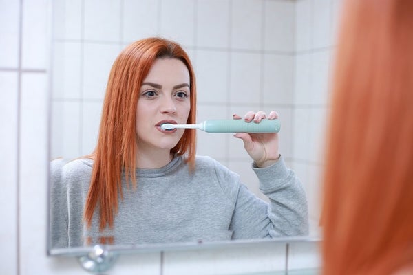 歯磨きしながら鏡を見る女性
