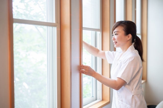 窓を開けて換気をする女性