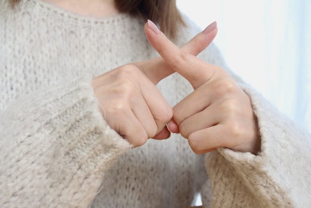 手で×のサインを作っている女性