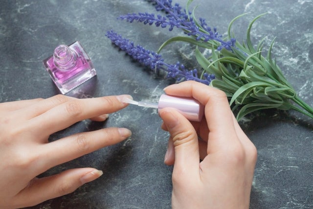 マニキュアを塗っている手と花