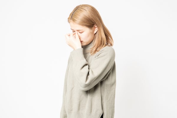 目頭と鼻の付け根を押さえる女性