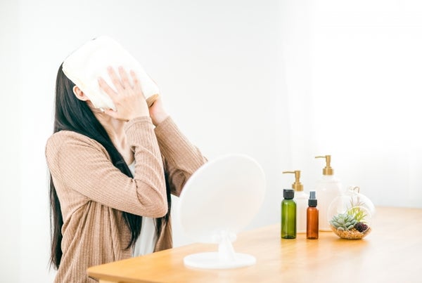 ホットタオルを顔に当てる女性