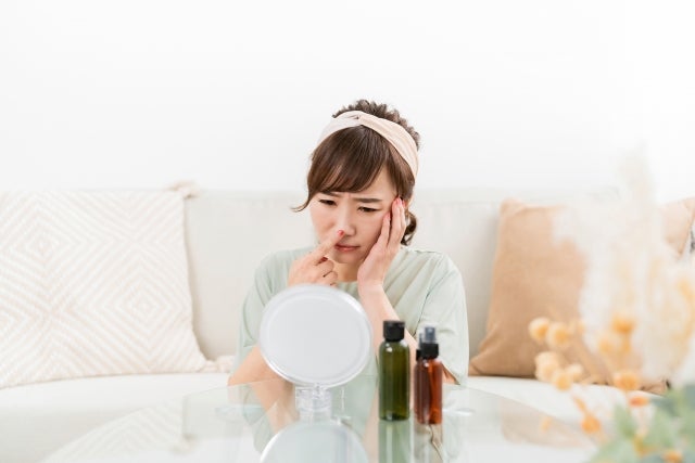 鏡を見て毛穴のチェックをする女性