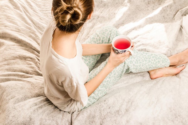 ベッドの上で飲み物を飲む女性
