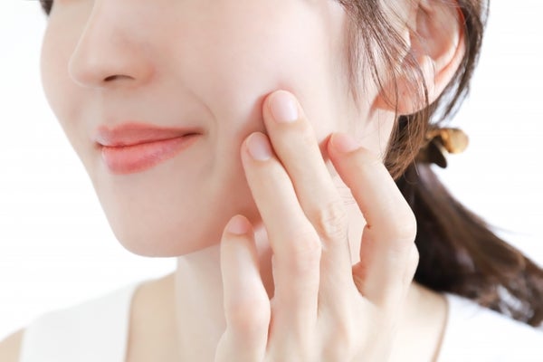 頬を押さえている女性の口元