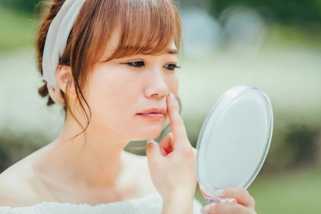 鏡を見て肌を気にしている女性
