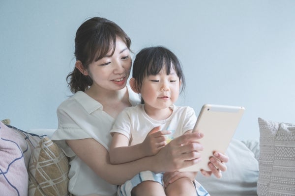 ソファーでタブレットを眺めている親子