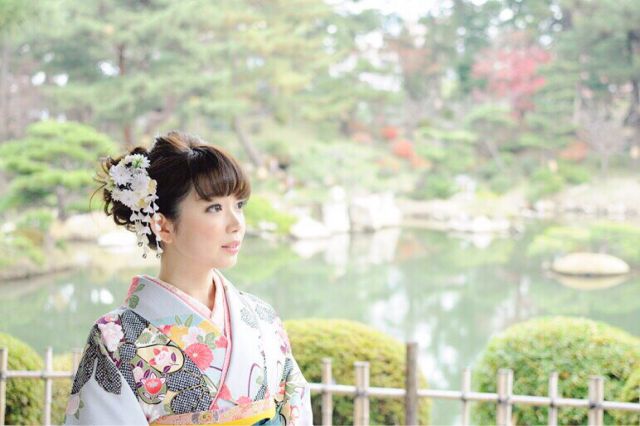 和装で日本庭園にたたずむ女性