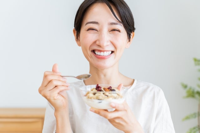笑顔でグラノーラを食べる女性