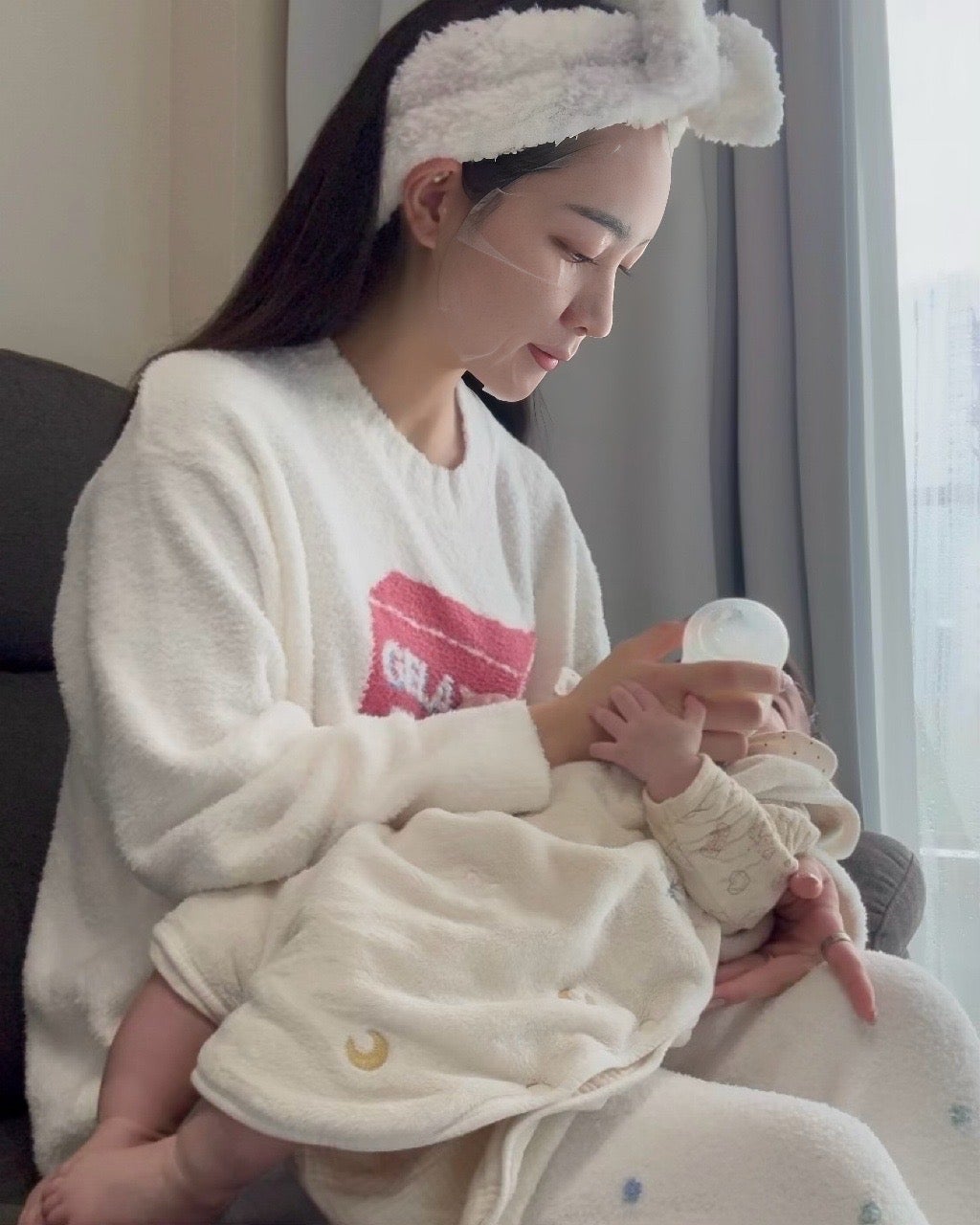 シートパックを顔に貼りながら0歳の子供に授乳をしている、はるさん