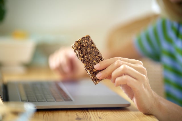 パソコン作業をしながら完全栄養食を持っている女性