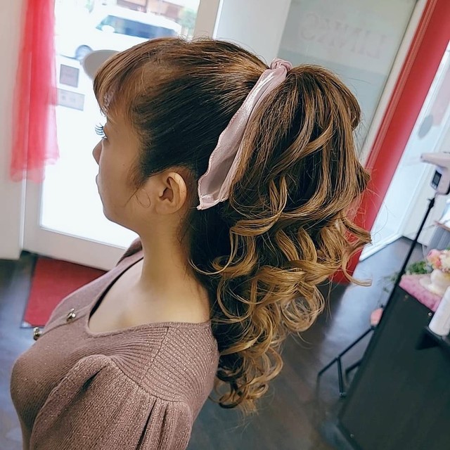 カールアイロンで全体を巻いて海外ガール風ポニテの女性