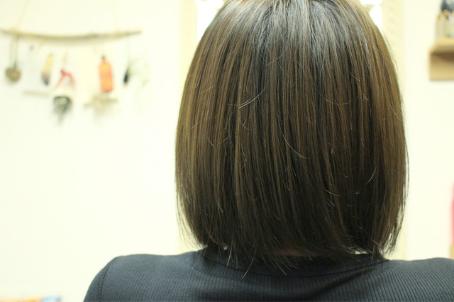 アッシュグリーンカラーの切りっぱなしボブスタイルの女性の後ろ姿