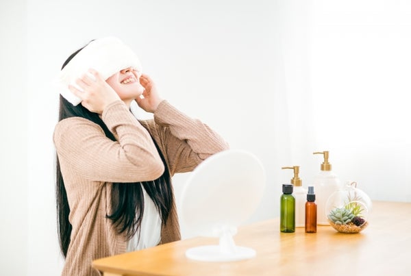 目にホットタオルをあてる女性