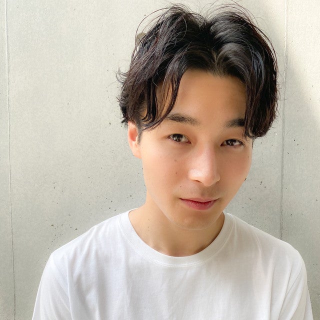 暗髪のセンターパートの髪型が似合う男性。