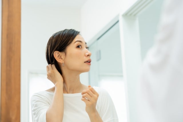 髪を触っているショートヘアの女性