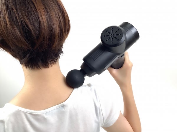 マッサージガンを肩に当てる女性