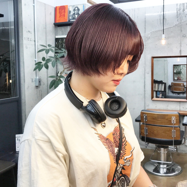 ヘッドフォンを首からぶら下げたショートカットの女性