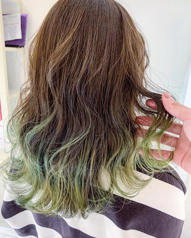 明るめのアッシュグリーンカラーをグラデーションで取り入れたヘアスタイルの女性