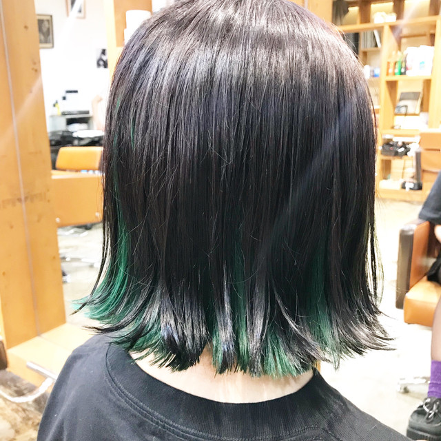インナーカラーに鮮やかなアッシュグリーンを取り入れた外ハネボブヘアの女性