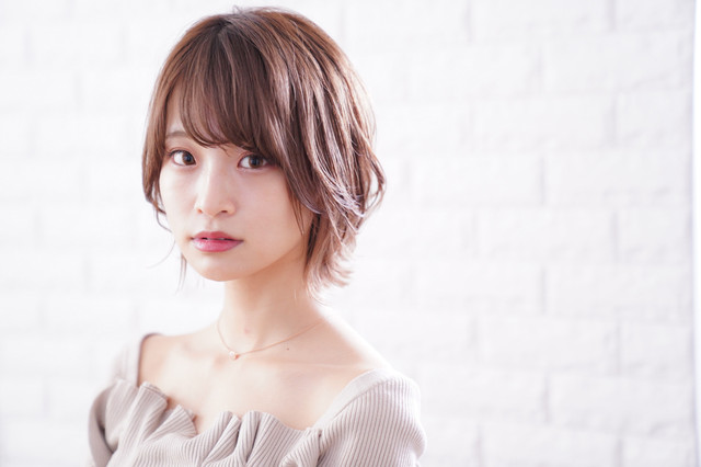 ピンク系の髪色をしたショートカットの女性