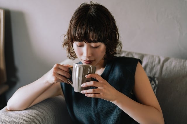 マグカップで飲み物を飲んでいる女性