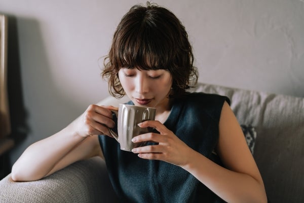 マグカップで飲み物を飲んでいる女性