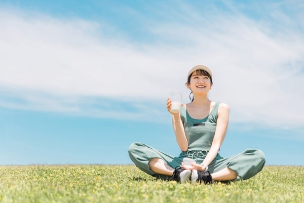 芝生の上でプロテインを飲む女性