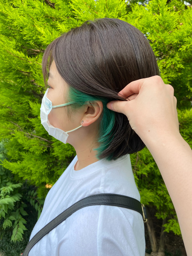 インナーカラーにアッシュグリーンを取り入れたボブスタイルの女性