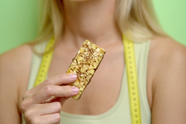 手にプロテインバーを持っている女性