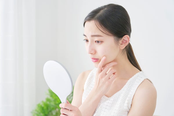 悩ましげに鏡を見る女性