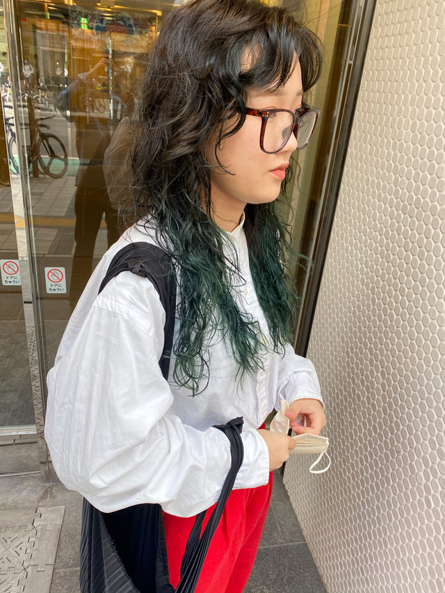 インナーカラーにアッシュグリーンを取り入れたロングウェーブスタイルの女性