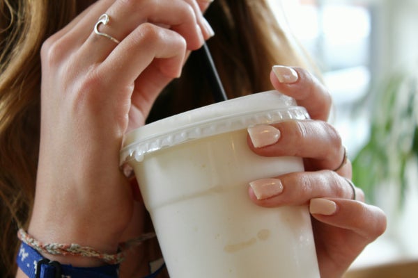 プラスチックカップでスムージを飲む女性
