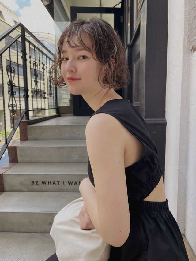 階段のところにいるパーマをかけたショートカットの女性