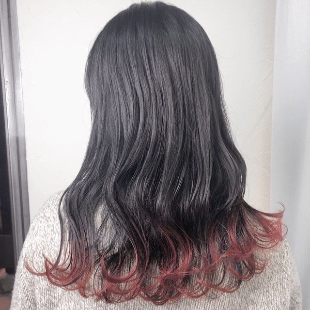 ダークブラウンカラーの毛先だけに、あざやかな暖色系のヘアカラーを入れた女性。